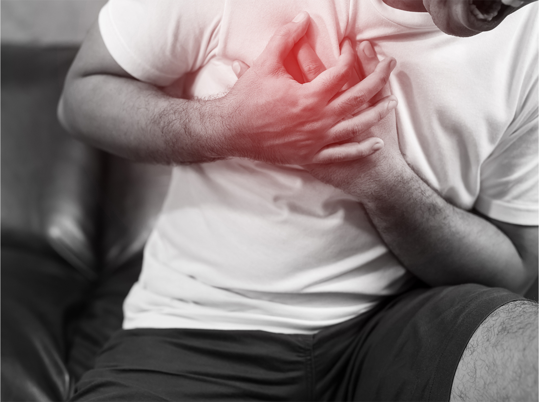 Man seated on a couch clutching his chest in pain, with the chest area highlighted in red to indicate distress.